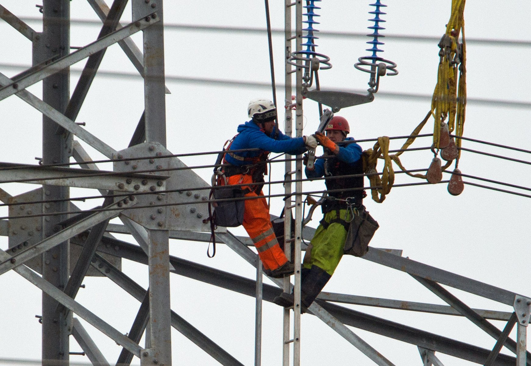 In schwindelerregender Höhe arbeiten Monteure einer Spezialfirma am 10.03.2013 in Eschborn (Hessen) an der Fertigstellung einer Überland-Starkstromleitung. Trotz Regen und Temperaturen von gerade mal vier Grad müssen die Männer auch mehr als fünzig Meter über dem Boden zentimetergenau arbeiten. Foto: Boris Roessler dpa 