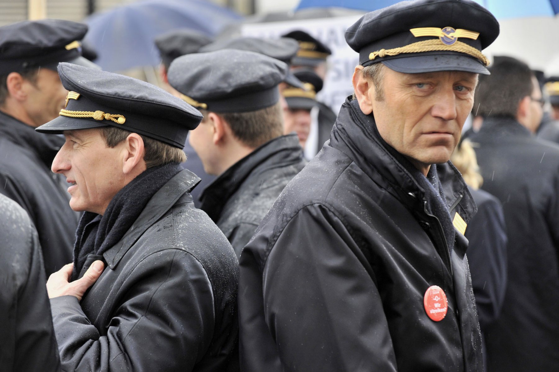 Im strömenden Regen nehmen Piloten der Lufthansa am Flughafen in Frankfurt am Main an einer Protestkundgebung teil. Foto: Boris Roessler/dpa  
