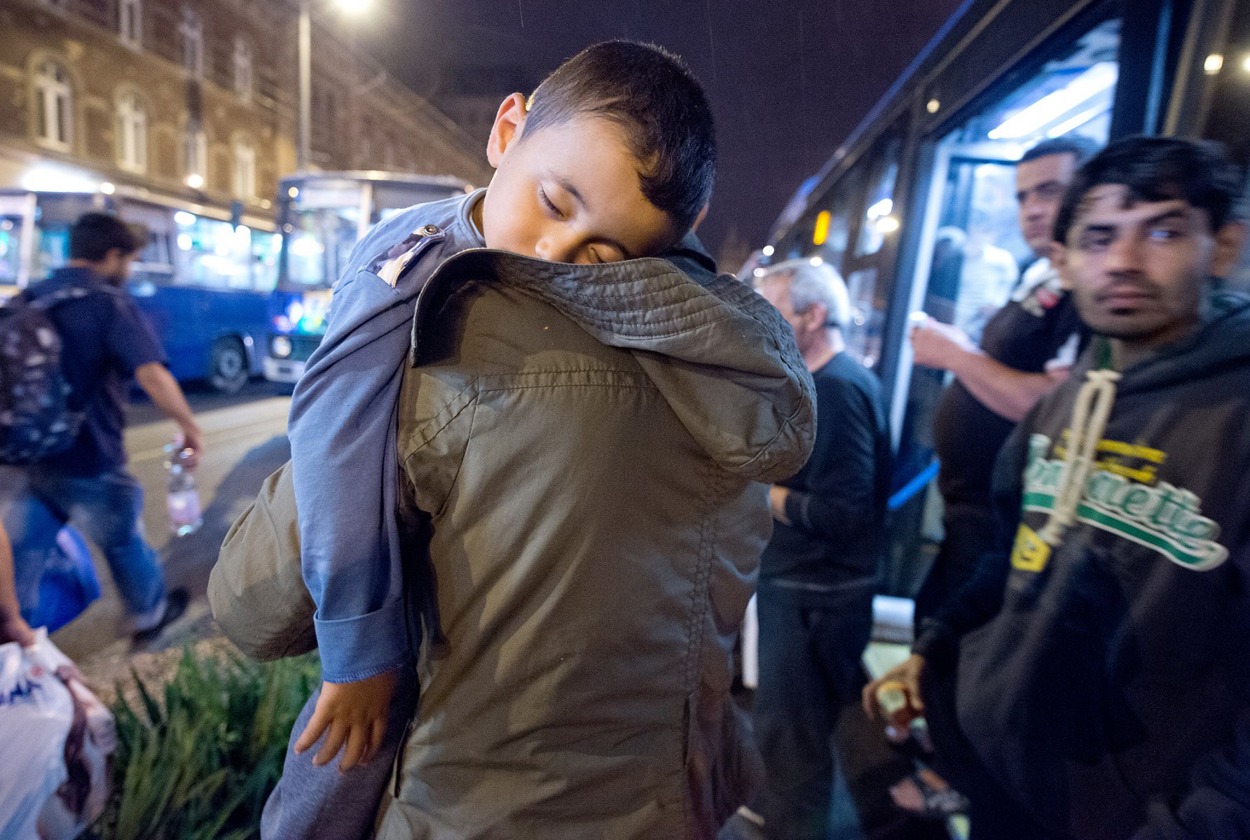 Mitten in der Nacht erreicht tausende Flüchtlinge im am 5. September 2015 vor dem Keleti-Bahmhof in Budapest die Nachricht, dass Sie nach Wochen der Ungewissheit Ungarn verlassen dürfen. Mit seinem schlafenden Sohn über der Schulter hastet ein Vater durch die Nacht. Foto: Boris Roessler/dpa