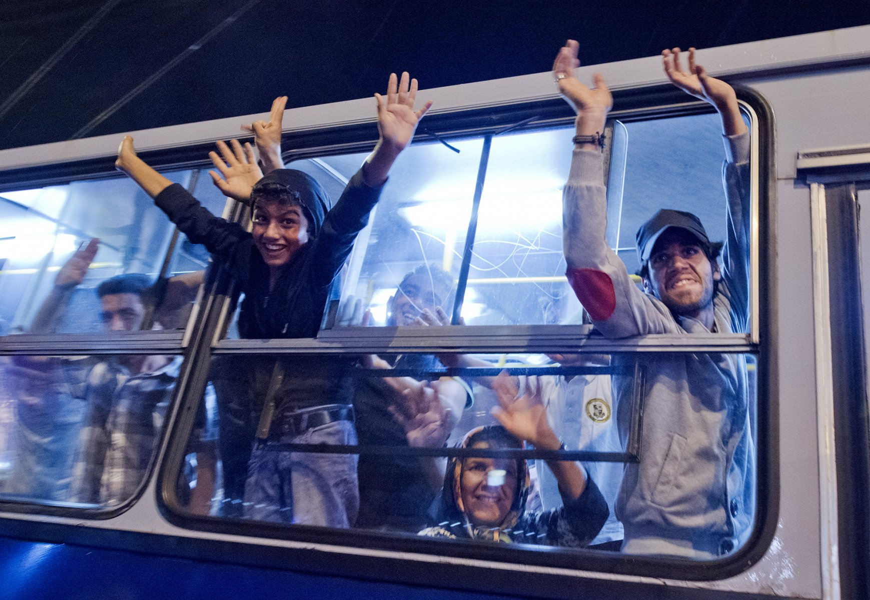 Mitten in der Nacht erreicht tausende Flüchtlinge im am 5. September 2015 vor dem Keleti-Bahmhof in Budapest die Nachricht, dass Sie nach Wochen der Ungewissheit Ungarn verlassen dürfen. Jubelnd steigen die Menschen in bereitgestellte Busse. Foto: Boris Roessler/dpa