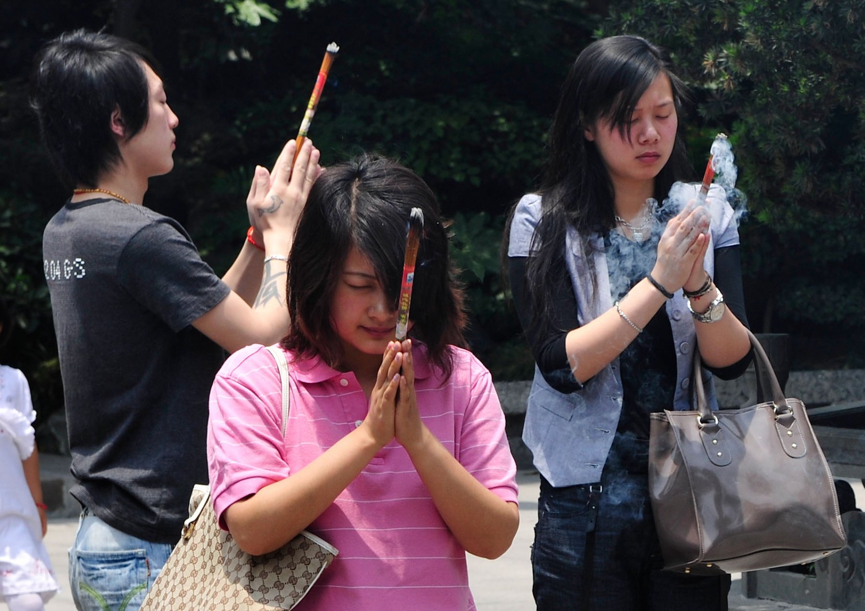 Mit brennenden Räucherstäbchen in den Händen verharren junge Chinesen minutenlang zum Gebet. Foto: Boris Roessler