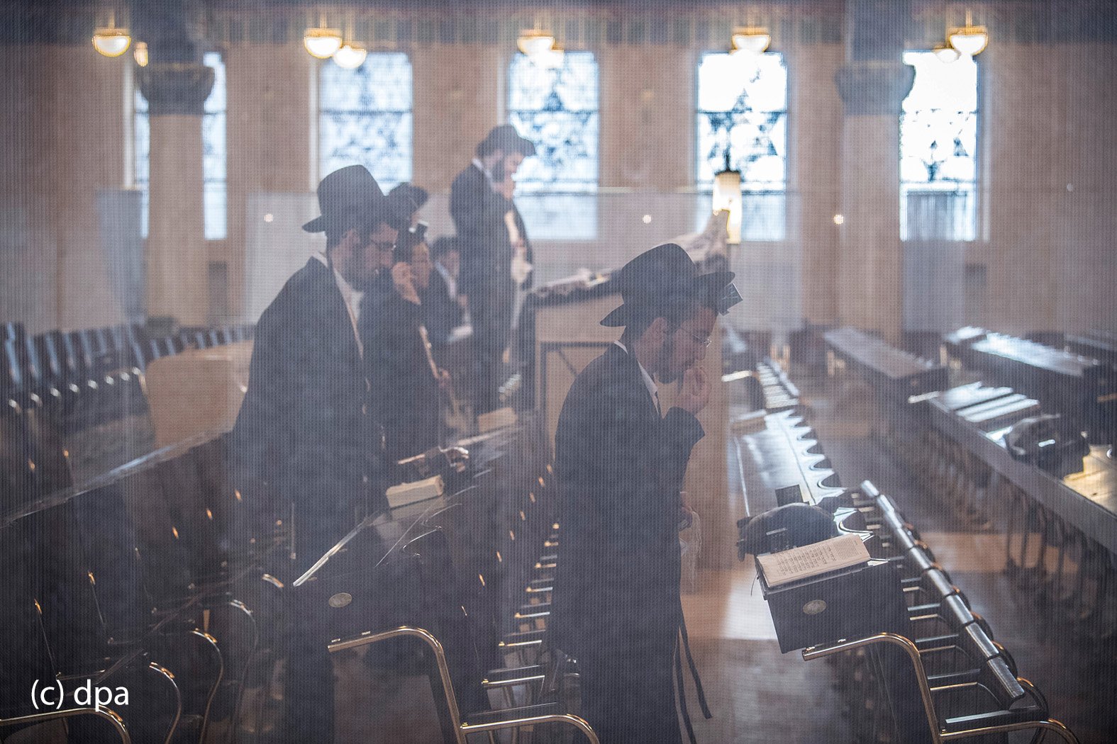 Ein engmaschiger Metallvorhang lässt den Blick auf Betende in der in der Westend-Synagoge in Frankfurt am Main leicht verschleiert erscheinen. In der Synagoge kommen die Gläubigen aus unterschiedlichen Glaubensausrichtungen bis zu dreimal täglich zum Gebet zusammen. 